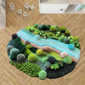 Puede incluir: Una alfombra redonda con un diseño de paisaje texturizado creado con numerosos pompones en varios tonos de verde, azul y beige. La alfombra representa un río sinuoso que fluye a través de un campo con grupos de pompones como árboles.