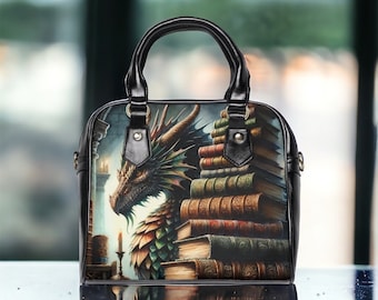 May include: Black handbag featuring a dragon illustration with a stack of books. The bag has a top handle and a shoulder strap. The dragon is depicted with green, brown, and black scales. The books are various sizes and colors.