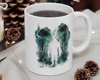 May include: White ceramic mug with a watercolor design of a large, white figure standing in a dark green forest. The figure is surrounded by trees and foliage.