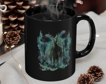 May include: Black coffee mug with a watercolor design of a forest scene. The design features a dark green and blue color scheme with a silhouette of a person standing in the forest.
