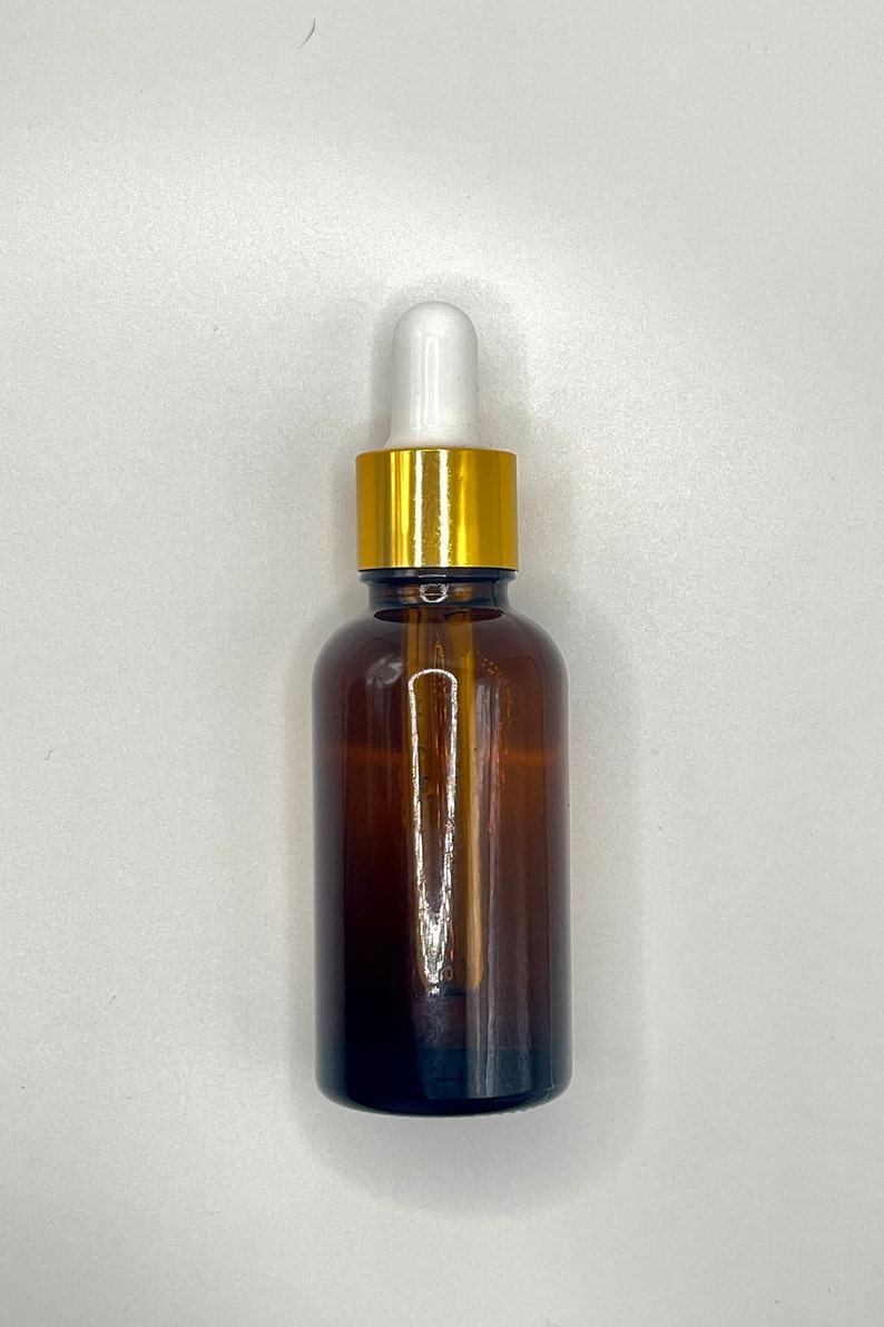 May include: A brown glass bottle with a gold lid and a white dropper. The bottle is filled with a clear liquid.