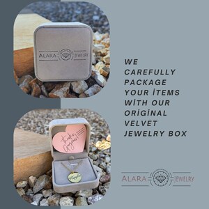 May include: A gold necklace with a round pendant that says "Kayla" in a cursive font. The necklace is displayed in a pink velvet jewelry box with a heart-shaped card that says "Thanks Gorgeous!" The box is sitting on a bed of small, gray rocks. The image also includes the text "ALARA JEWELRY" and "WE CAREFULLY PACKAGE YOUR ITEMS WITH OUR ORIGINAL VELVET JEWELRY BOX".