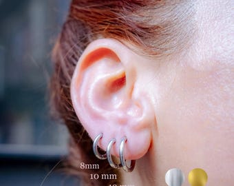 May include: Close-up of an ear with three silver hoop earrings. The earrings are 8mm, 10mm, and 12mm in diameter. The image also shows a silver and a gold color swatch.