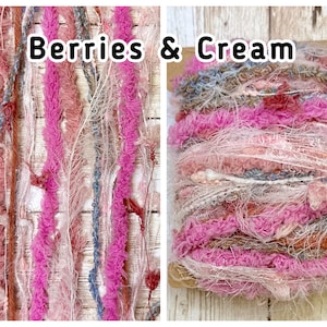 May include: Textured yarn in pink, cream, and blue. The yarn is labelled "Berries & Cream" and is suitable for various craft projects. The yarn is on a wooden surface. The yarn is suitable for knitting and crochet.