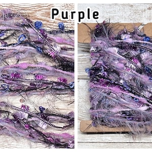 May include: A spool of purple yarn with a mix of textures, including fuzzy, metallic, and beaded elements. The yarn is a blend of light and dark purples, black, and silver, with the word "Purple" in the image.