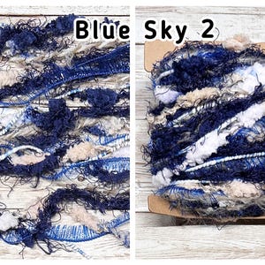 May include: Two images of Blue Sky 2 yarn. The yarn is a mix of dark blue, light blue, white, and beige fibres. The yarn has a textured, fluffy appearance. The text "Blue Sky 2" is visible in the image.