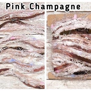 May include: A spool of Pink Champagne yarn featuring a mix of textures, including fuzzy white fibres, metallic copper ribbons, and small pink and light blue accents. The yarn is wrapped around a rectangular cardboard bobbin.