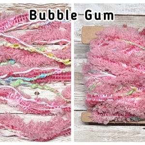 May include: Bubble Gum textured yarn in shades of pink, with accents of white, yellow, and blue. The yarn is shown in two arrangements, one loose and one wound on a wooden spool. The text "Bubble Gum" is displayed above the yarn.
