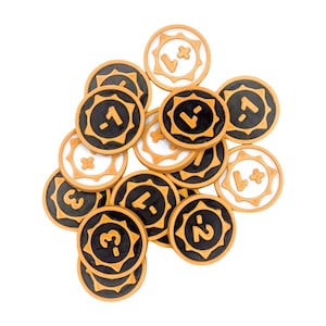 May include: A pile of 14 round, gold-coloured game tokens with black and white numbers and symbols. The tokens have a sunburst design around the edges.