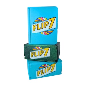 Puede incluir: Tres cajas de juego Flip 7 apiladas, de color verde azulado y verde. Cada caja tiene las palabras "Flip 7" en una fuente amarilla con un diseño de arcoíris. Las cajas superior e inferior son de color verde azulado, y la caja del medio es verde.