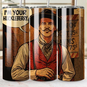May include: A stainless steel tumbler featuring a stylized illustration of a cowboy with the text "I'M YOUR HUCKLEBERRY." The design includes a cowboy in a hat and vest, with a speech bubble. The tumbler has a straw.