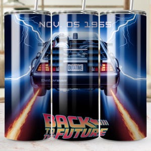 以下が含まれることがあります： 青い背景に、映画「バック・トゥ・ザ・フューチャー」の銀色のデロリアンタイムマシンが描かれたステンレス製のタンブラー。車はオレンジ色の炎に囲まれ、車の真下に「バック・トゥ・ザ・フューチャー」という文字が印刷されています。車の真上に「Nov. 05 1955」という文字が印刷されています。