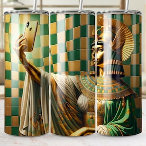 May include: A stainless steel tumbler with a green and gold checkered background. A golden figure of a woman with a headdress and jewelry is taking a selfie with a gold iPhone.