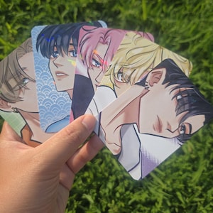 May include: A set of four rectangular trading cards featuring anime-style illustrations of characters with distinct hair colors including blonde, pink, and black. Each card displays a portrait with a unique background pattern and holographic finish.