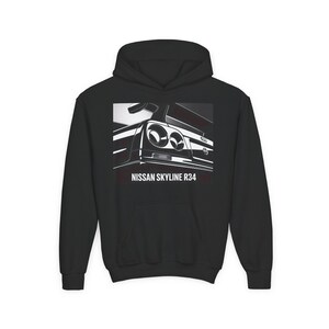 May include: Black hooded sweatshirt featuring a graphic of a Nissan Skyline R34 car. The graphic is in black and white, showcasing the rear of the vehicle with the text "NISSAN SKYLINE R34" below the image.