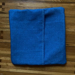 Pode incluir: Uma capa de almofada azul com uma costura branca no centro.