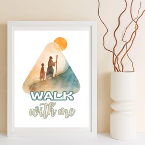 May include: White framed art print featuring a watercolor illustration of two figures walking up a hill towards a sun. The words "WALK with me" are written in a teal and cursive font. A white vase with brown branches is to the right.