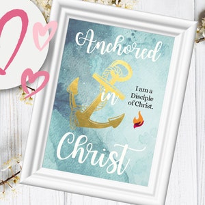 May include: A framed print with a watercolor background in shades of blue and green. A gold anchor is in the center of the print with the words "Anchored in Christ" written in white cursive. The text "I am a Disciple of Christ." is written in black below the anchor. A small red flame is below the text.