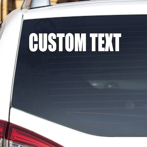 May include: White vinyl decal with the text "CUSTOM TEXT" on a car window.