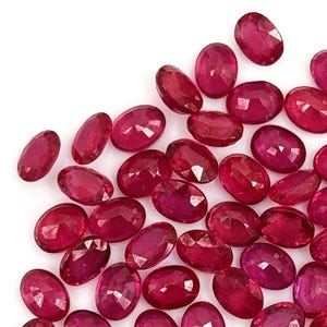 Peut inclure: Un ensemble de rubis de forme ovale, aux nuances de rouge et de rose. Les pierres précieuses sont dispersées sur un fond blanc, mettant en valeur leurs facettes et leur éclat. Ces rubis sont parfaits pour la joaillerie.