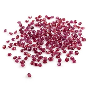 Op de afbeelding: Een hoop losse, ronde, rode edelstenen op een witte achtergrond.
