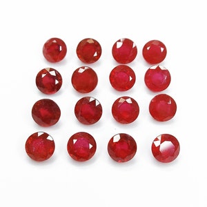 Puede incluir: Una colección de 16 piedras preciosas redondas de color rojo. Las piedras preciosas están dispuestas en una cuadrícula sobre un fondo blanco.