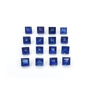 Könnte beinhalten: Eine Sammlung von 16 quadratischen, facettierten Saphirsteinen, die in einem Gittermuster angeordnet sind. Die Saphire sind tiefblau und auf einem weißen Hintergrund platziert.