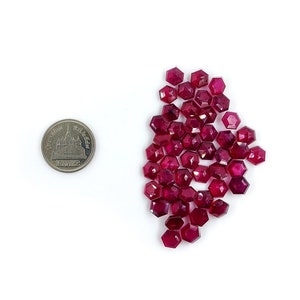 May include: A pile of ruby red gemstone beads, approximately the size of a US quarter.