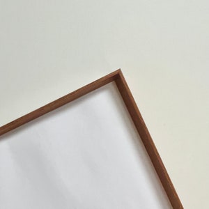 May include: A wooden frame with a white background. The frame is brown and has a simple, clean design.