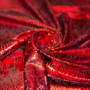 Peut inclure: Gros plan sur un tissu rouge vif avec un motif peau de serpent. Le matériau a un éclat métallique, reflétant la lumière et créant des reflets. Le tissu est drapé et plié, mettant en valeur sa texture et son design. L'effet global est luxueux et accrocheur.