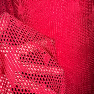 Puede incluir: Tela de malla roja con un tejido fino y uniforme. La tela es suave y flexible, y tiene una superficie ligeramente texturizada.