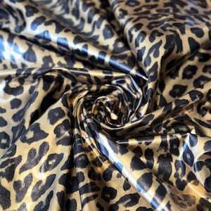 May include: Gold and black leopard print fabric with a shiny, satin-like finish.