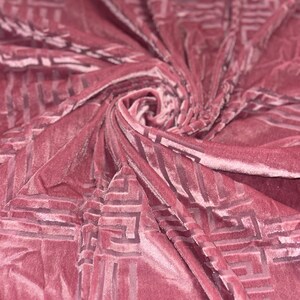May include: A close-up of a pink velvet fabric with a geometric pattern. The fabric is soft and luxurious, and the pattern is subtle and elegant.