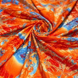Op de afbeelding: Oranje, blauwe en gouden stof met een marmerpatroon. De stof heeft een subtiele glans.