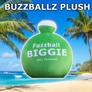 May include: Green plush toy shaped like a ball with the words "Fuzzball BIGGIE 100% Fuzziness" printed on it. The toy is sitting on a beach with palm trees in the background.