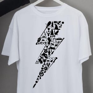 Puede incluir: Camiseta blanca con un diseño de rayo negro compuesto por varios iconos. Los iconos incluyen una escoba, un sombrero, gafas y otros símbolos. La camiseta está hecha de un material suave y tiene mangas cortas.