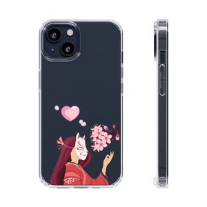 Pode incluir: Uma capa transparente para telefone com um coração rosa e uma mulher com uma máscara de raposa e flores de cerejeira rosa. A capa é projetada para um iPhone.