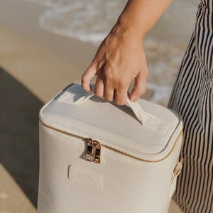 May include: A white canvas cooler bag with a gold zipper and handle. The bag has the word "SUMMCO" printed on the front.