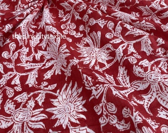 Pode incluir: Tecido de algodão vermelho com estampa floral branca. O tecido está dobrado e mostra o padrão.