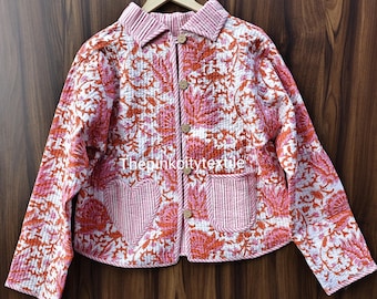 May include: A quilted jacket with a floral pattern in shades of pink and orange on a white background. The jacket has a collared neckline, wooden buttons, and two front pockets. The text "thepinkcitytextile" is visible on the jacket.