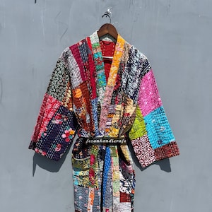 Może przedstawiać: Kolorowa kimono w stylu patchwork z długim, płynnym krojem. Kimono jest wykonane z różnych tkanin i kolorów, w tym czerwonego, niebieskiego, zielonego, żółtego i różowego. Kimono jest wiązane czarnym paskiem i ma etykietę "fezanhandicrafts".