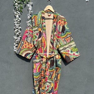 Pode incluir: Uma bata de kimono colorida e estampada com cinto para amarrar. A bata é feita de um tecido macio e acolchoado e apresenta uma variedade de cores e padrões, incluindo padrões paisley, florais e geométricos.