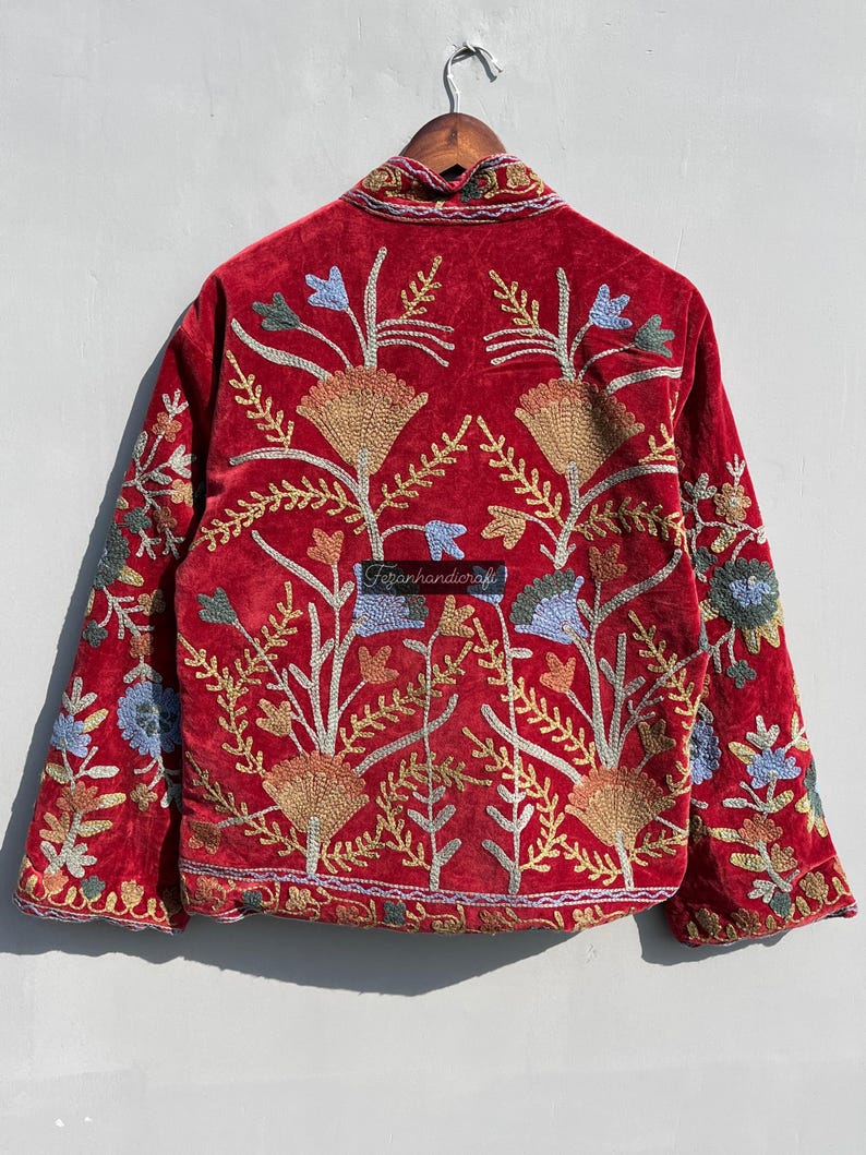May include: Red velvet jacket with intricate floral embroidery in shades of gold, blue, and green. The jacket has a mandarin collar and long sleeves.