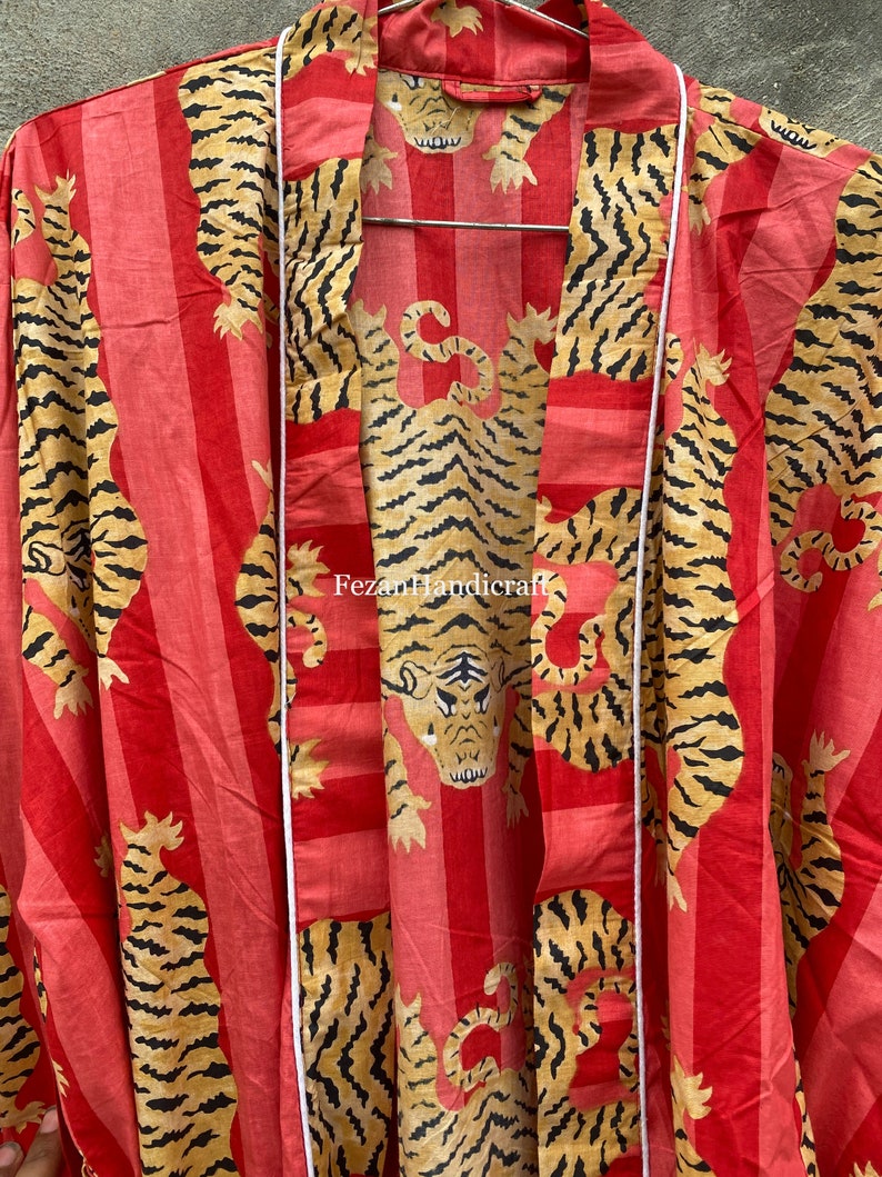 May include: A red and white striped kimono with a tiger print. The kimono has a white sash and the text "Fezan Handicraft" is printed on the front.