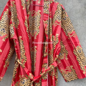 May include: A red and gold striped robe with a tiger print. The robe has a tie belt and long sleeves. The text "Fezan Handicraft" is visible on the robe.