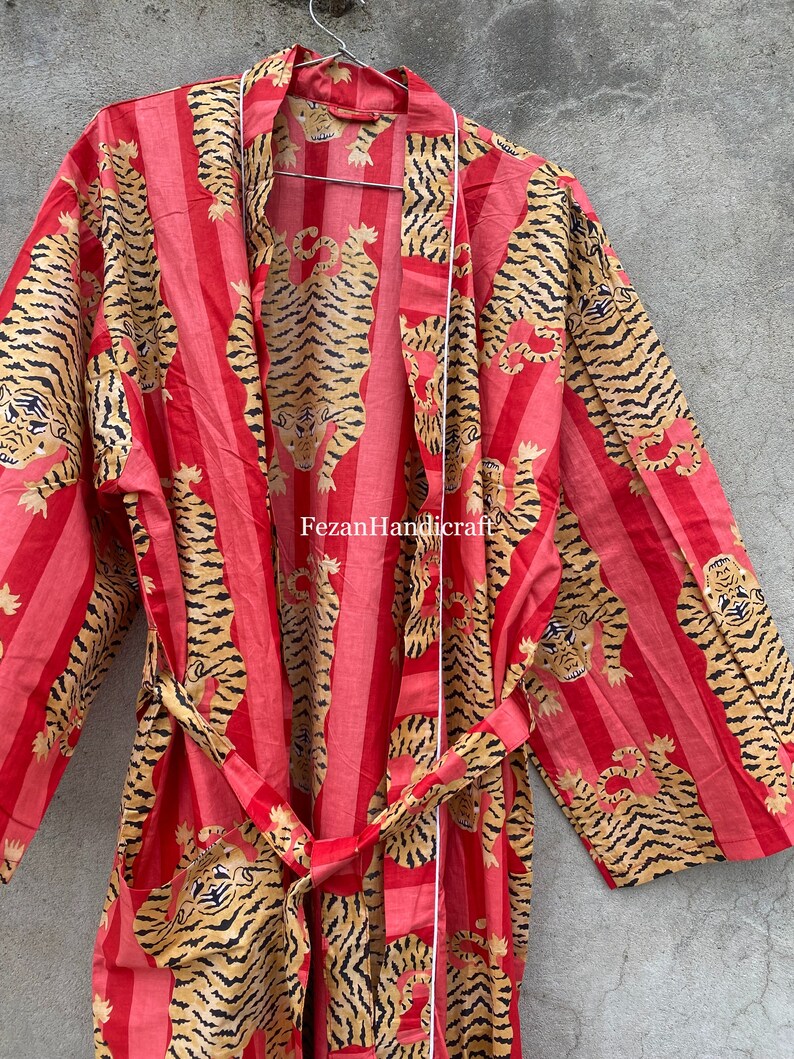 May include: A red and gold striped robe with a tiger print. The robe has a tie belt and long sleeves. The text "Fezan Handicraft" is visible on the robe.