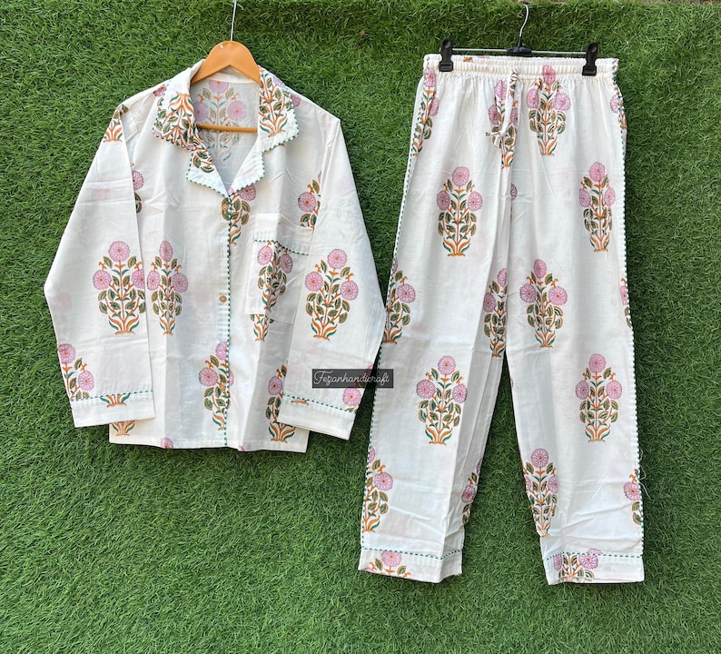 May include: White cotton pajama set with a floral print in pink and green. The top has a button-up front and long sleeves. The pants have an elastic waistband.