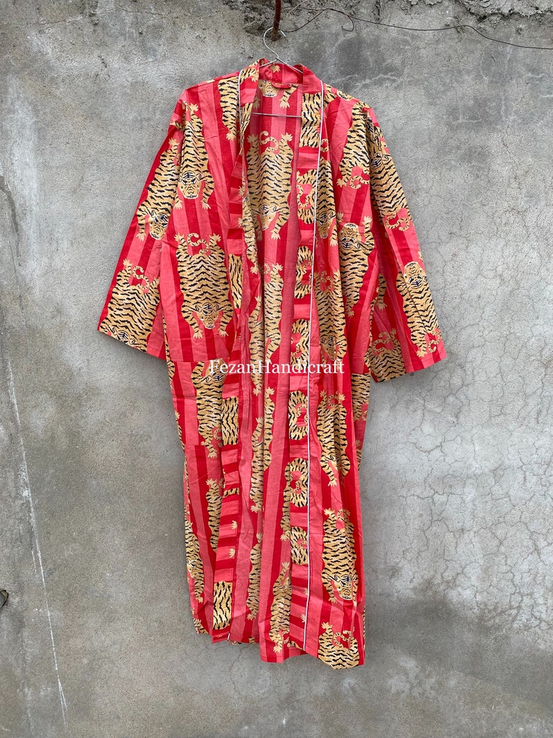 May include: A red and gold striped kimono with a tiger print. The kimono has a long, flowing silhouette and is perfect for layering over other clothing.