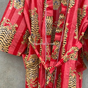 May include: A red and white striped robe with a tiger print. The robe has a white sash and is made of cotton.