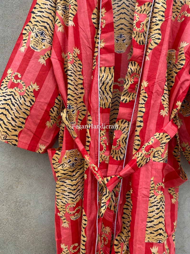 May include: A red and white striped robe with a tiger print. The robe has a white sash and is made of cotton.